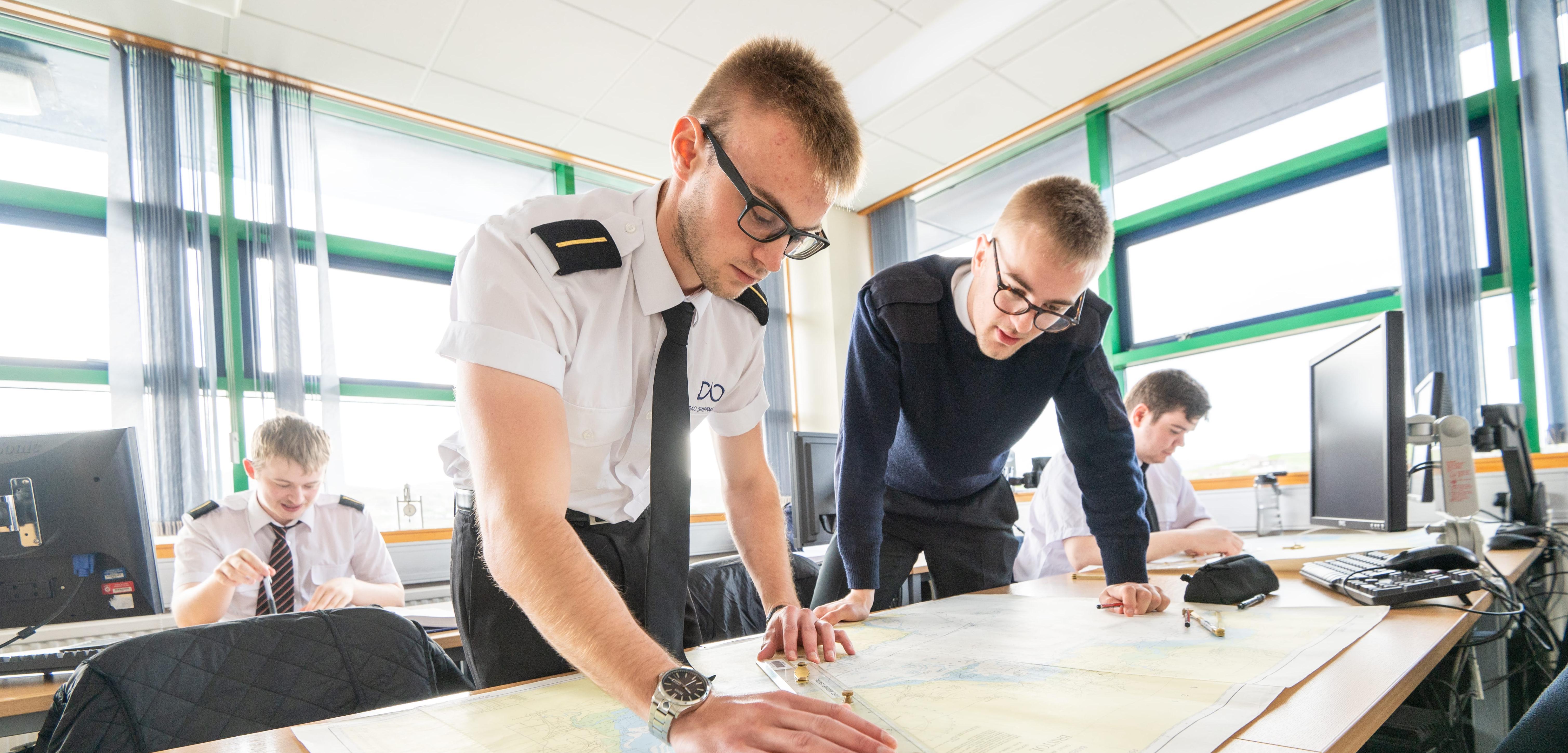 Merchant navy cadets looking at a sea chart